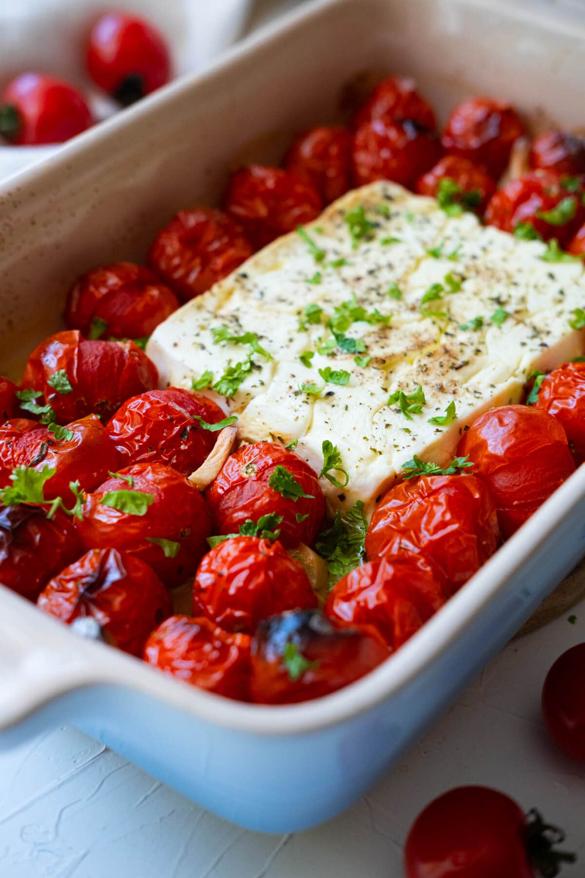 Bursting tomato and golden brown feta cheese baked in a baking dish. 