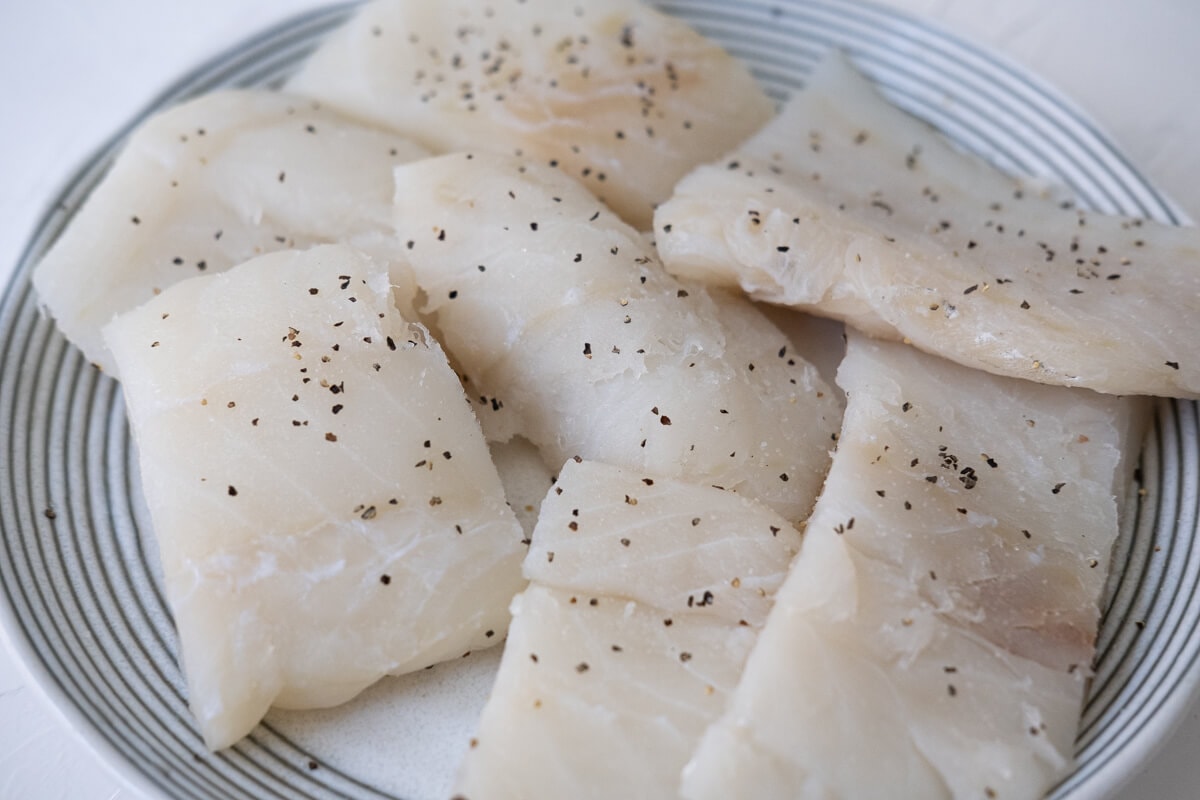 Fish seasoned with salt and pepper on a plate. 