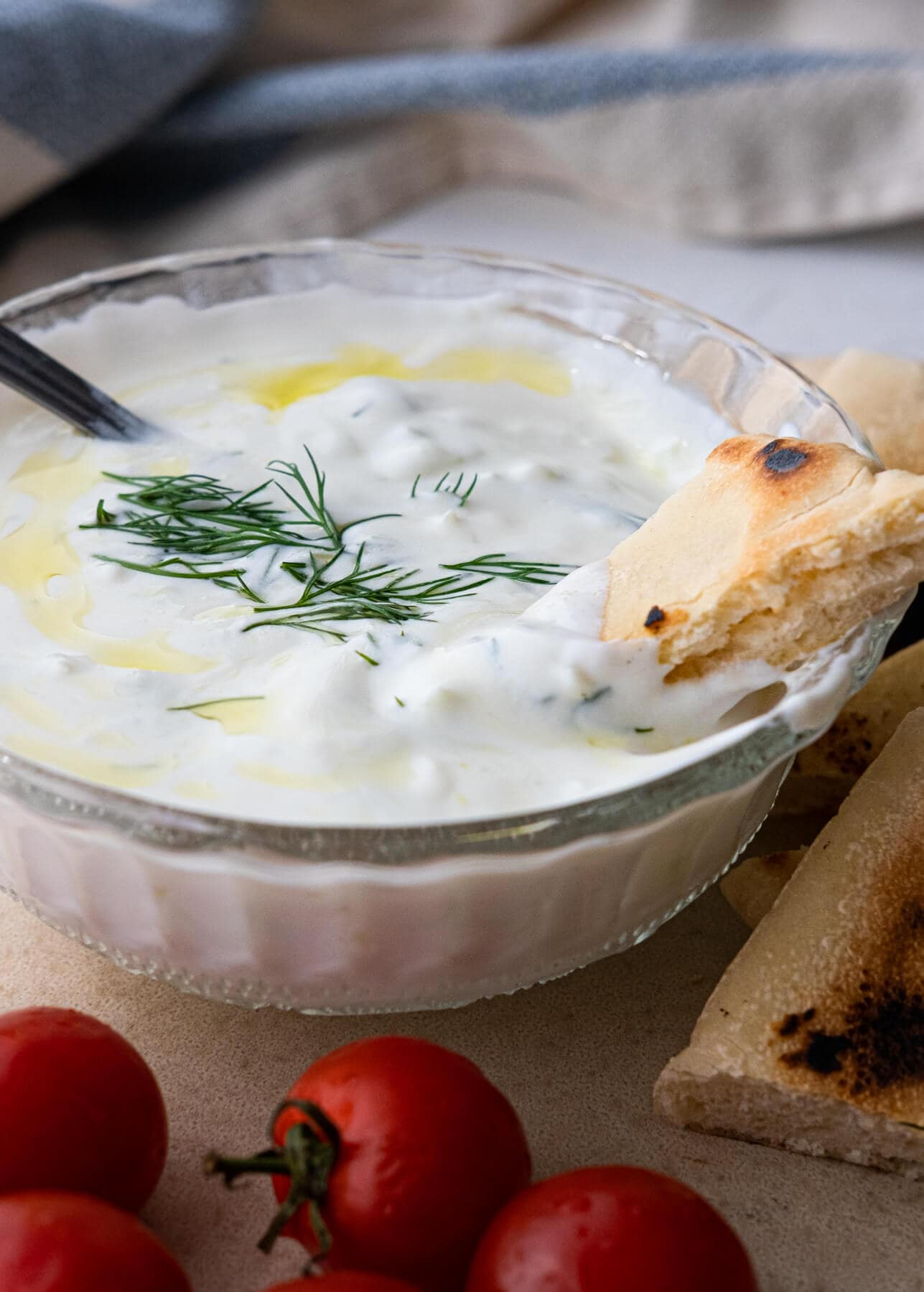 Pita bread dipped in creamy white tzatziki sauce in a bowl. 