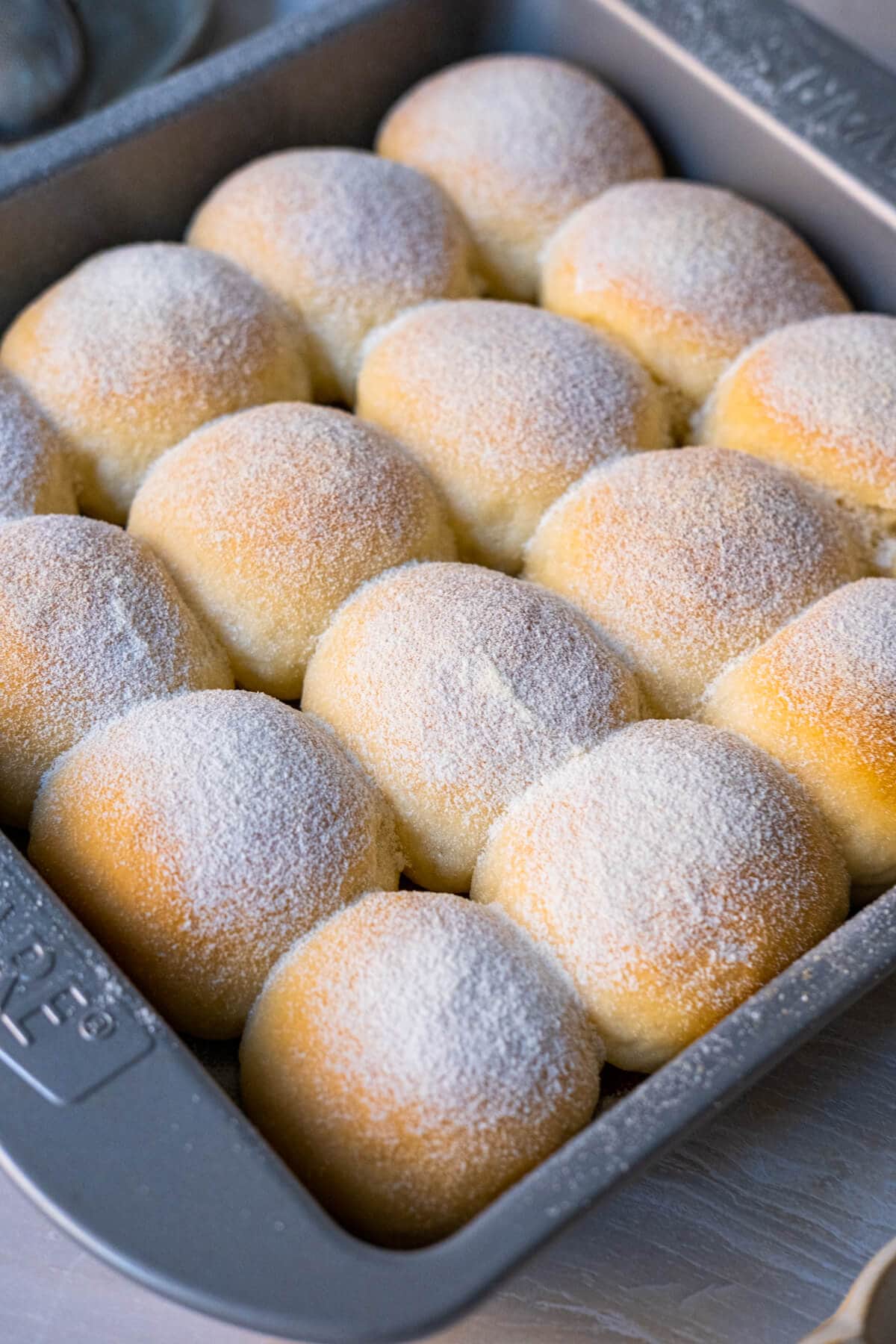 A tray of soft milk buns arranged in baking tray with golden exterior coated in sugar and milk powder mixture. 
