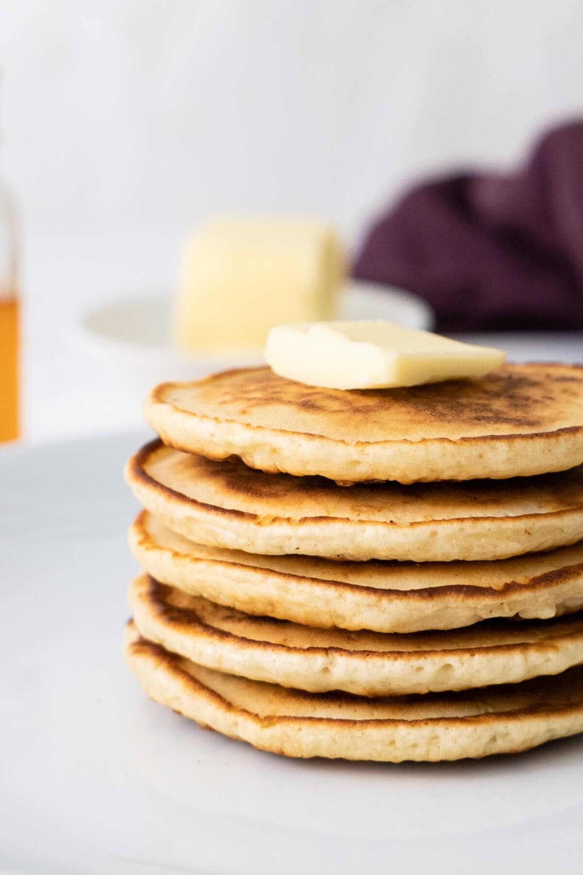 A side view of stacked scotch pancakes with a piece of butter on top.