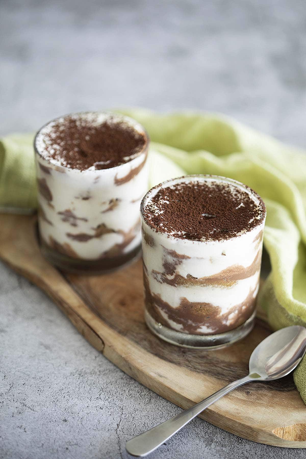 Two cups of classic Italian Tiramisu dessert featuring creamy fillings layered with coffee mixture in between. 