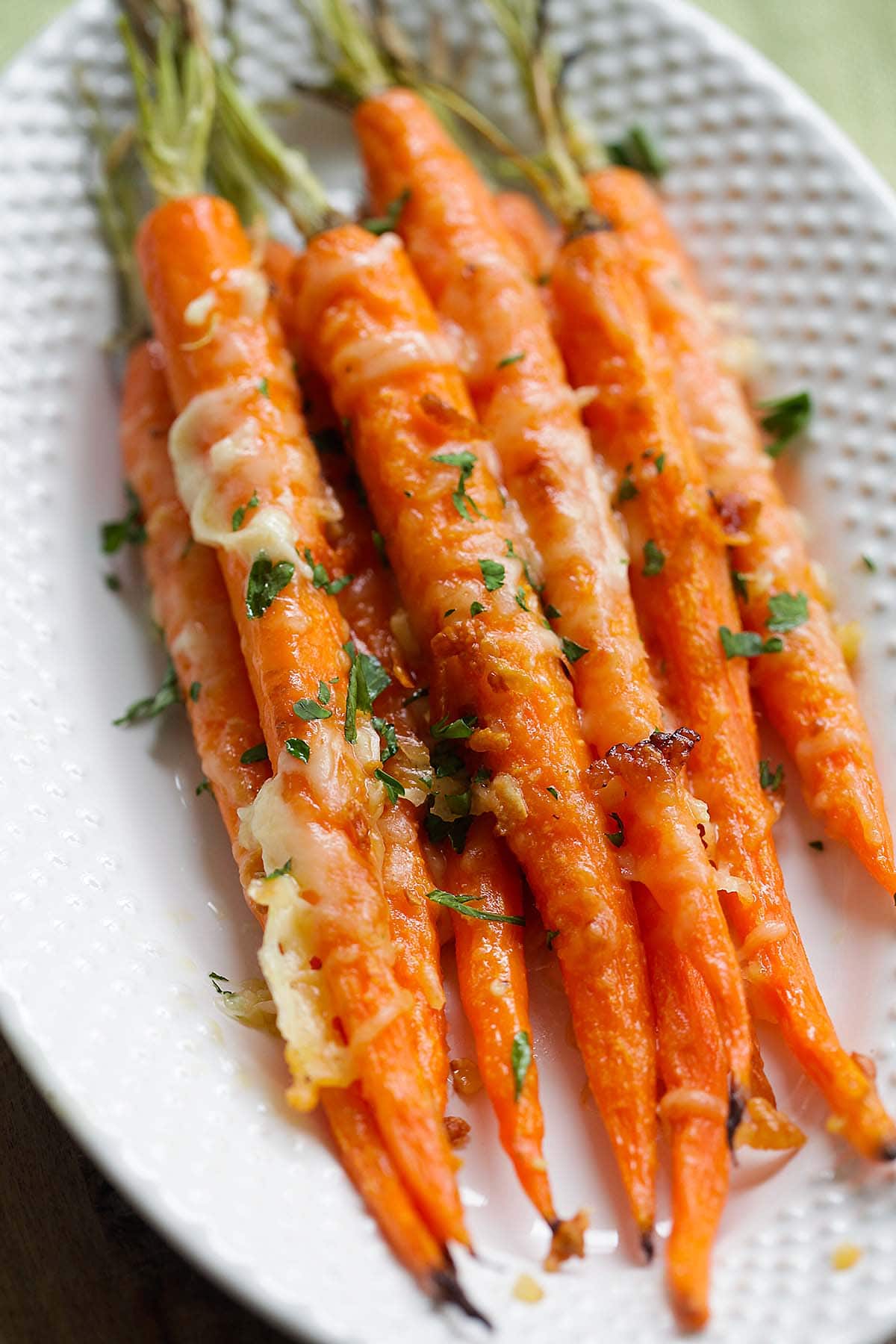 One of the best roasted carrot recipes made with carrot tops, garlic, butter and Parmesan cheese on a plate.