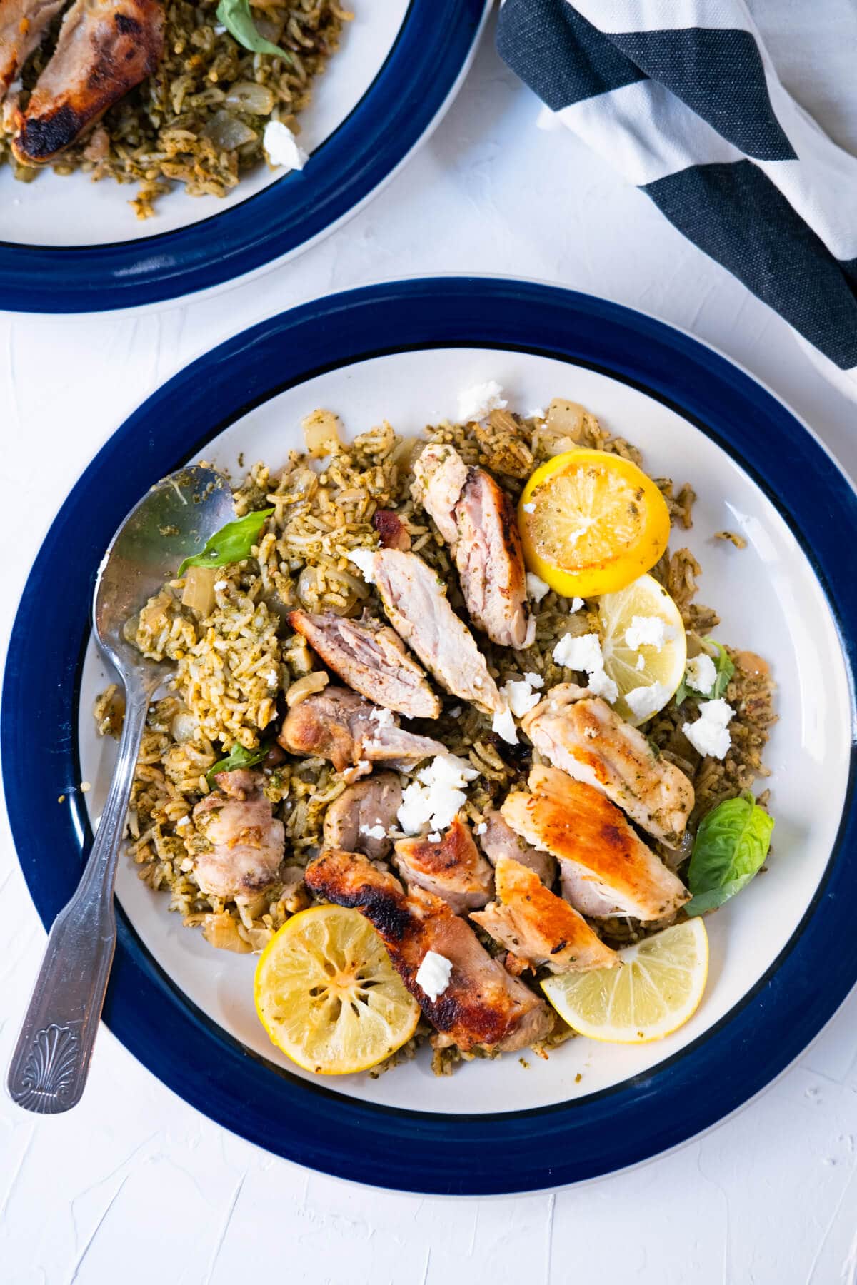 One-pan Greek chicken and rice is served with seared lemon slices and Feta cheese crumbles.