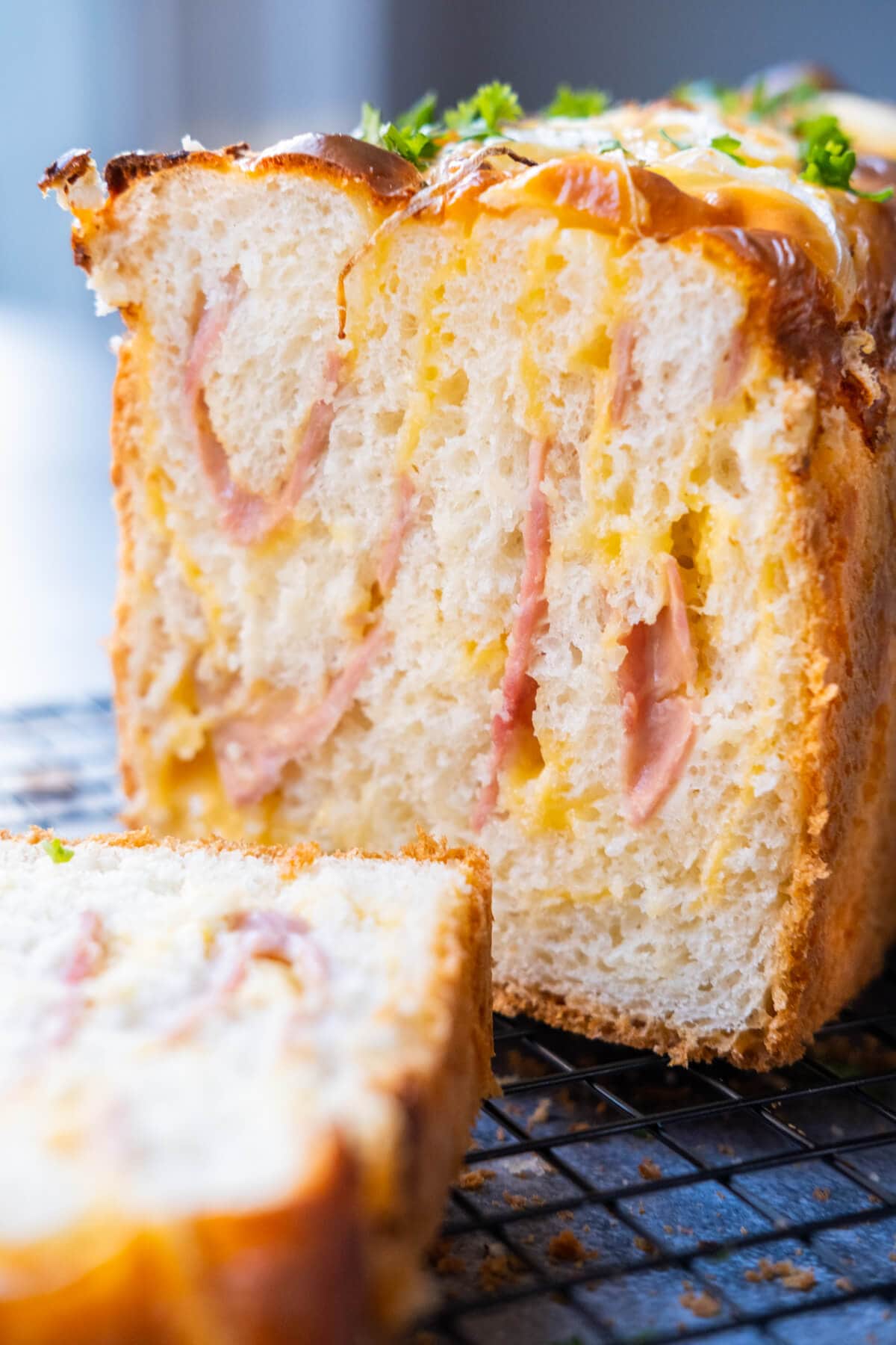 One loaf of bread with golden brown crust sliced into tempting pieces reveals the savory filling of ham and melted cheese.
