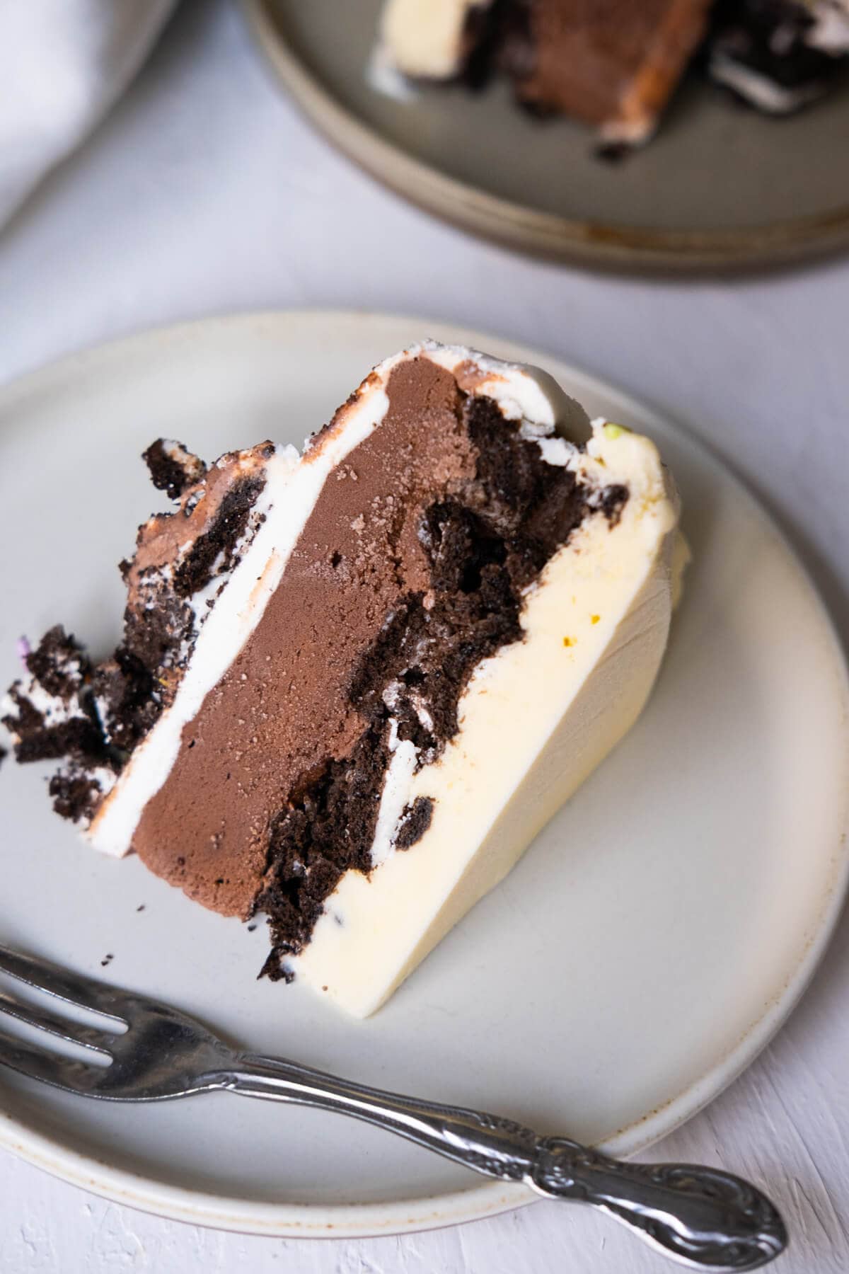 A slice of cake with chocolate ice cream, Oreo crumbs, and vanilla ice cream. 