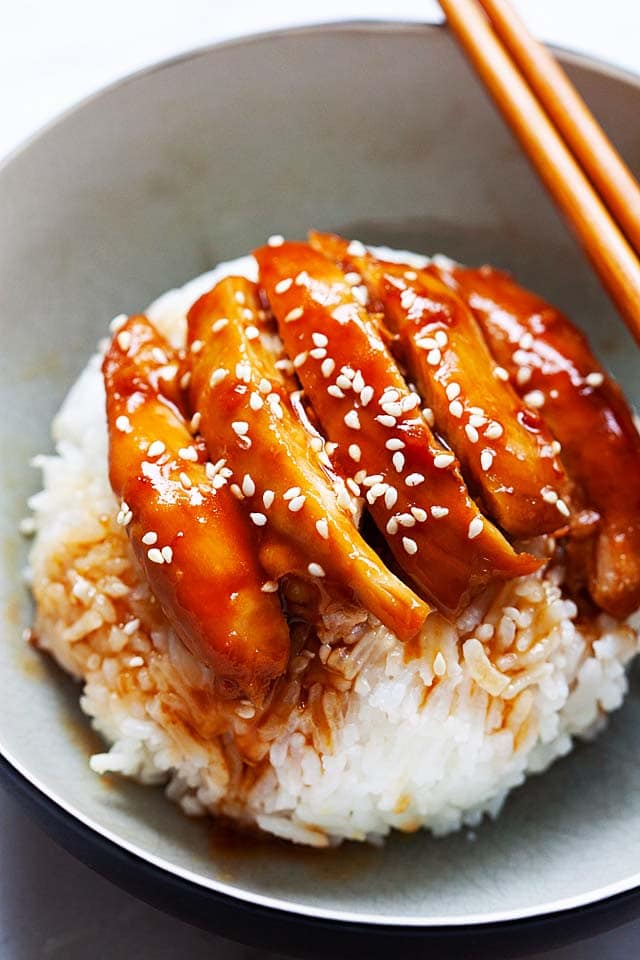 Chicken teriyaki with steamed rice in a bowl with a pair of chopsticks.