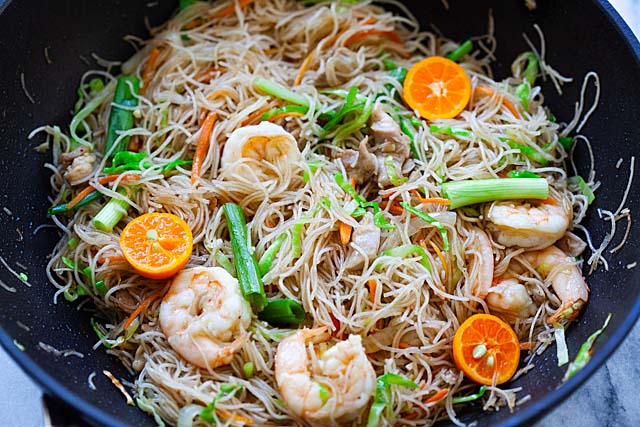 Shrimp pancit recipe with chicken and vegetables in a skillet.