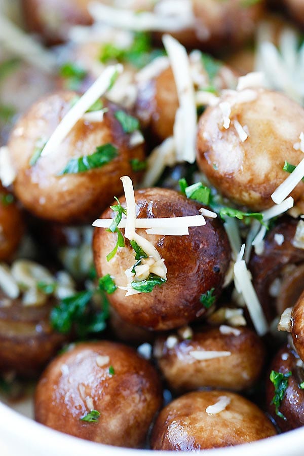 closeup image of button mushrooms sauteed with olive oil, garlic, parsley, and topped with Parmesan cheese.